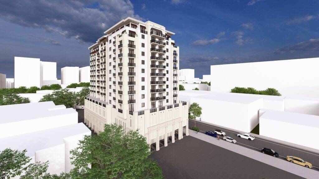 Modern high-rise building against a clear blue sky, surrounded by urban structures and trees.