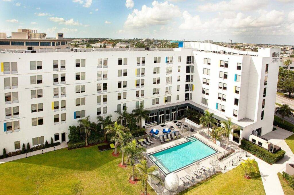 Aerial view of a modern hotel with a pool and lush greenery in Doral.