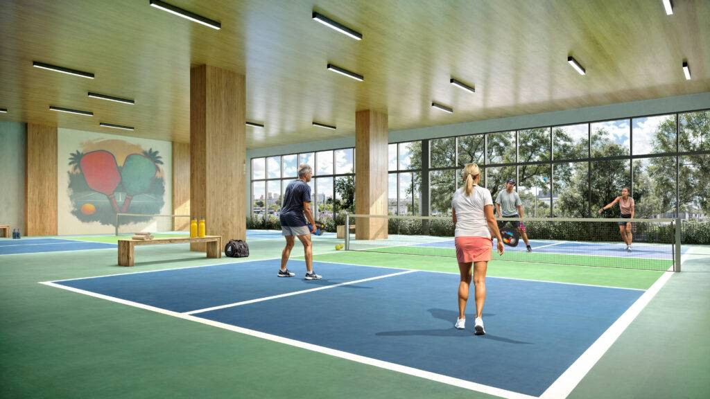 Indoor pickleball court with players enjoying a game surrounded by lush greenery outside the large windows.
