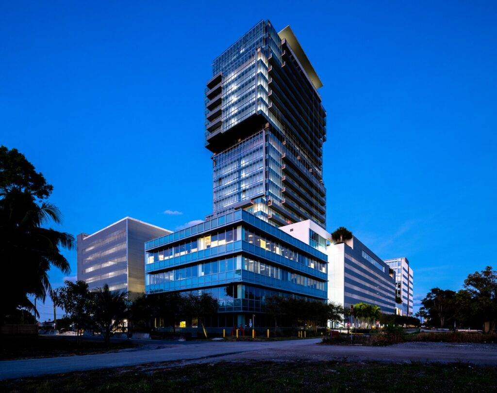 Modern skyscraper with glass facade against a twilight sky.