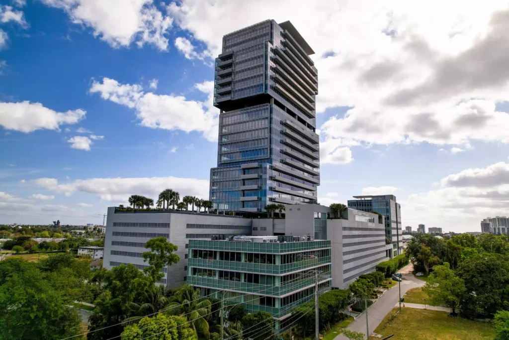 Modern high-rise building with lush greenery under a bright blue sky.