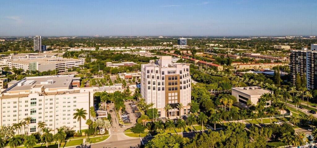 Aerial view of Aventura Country Club Center surrounded by lush greenery and urban skyline.