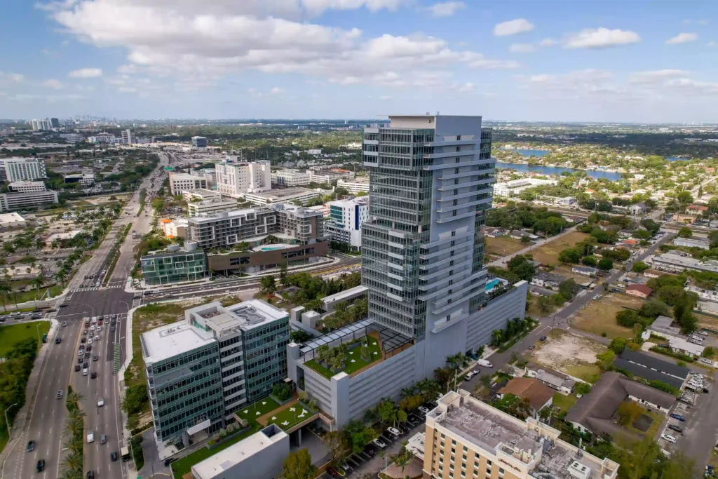 Aerial view of Aventura Optima Onyx tower in an urban landscape with blue skies.