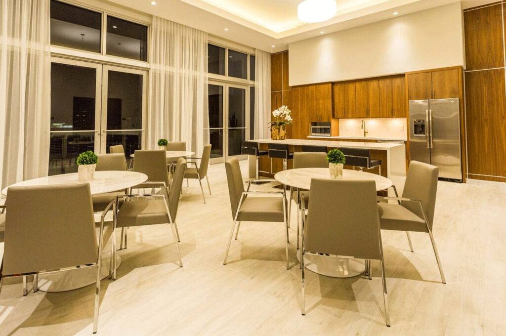 Elegant modern kitchen with wooden cabinets, stainless steel appliances, and round tables with chairs.