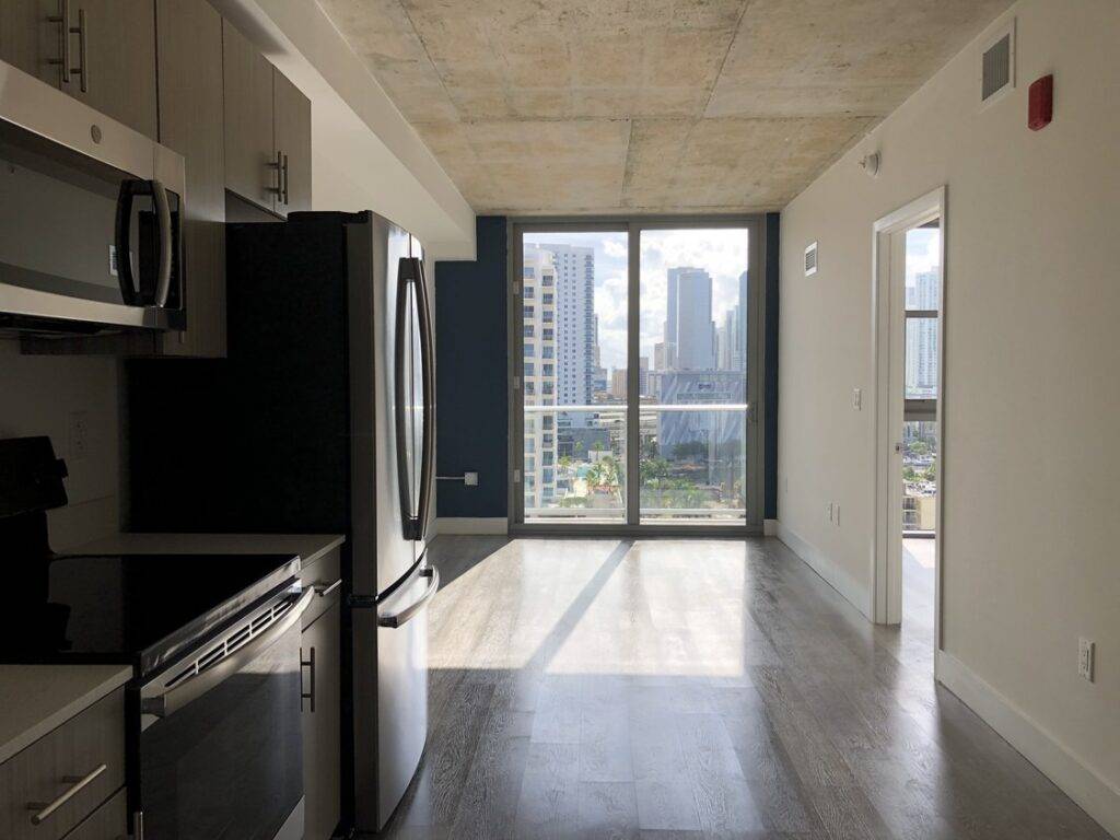 Modern apartment interior with kitchen appliances and city view through large window