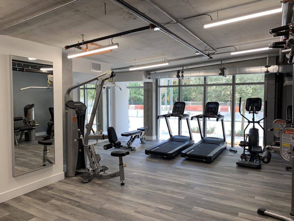 Modern gym with exercise equipment, treadmills, and bright windows. Sleek design and open space enhance workout experience.