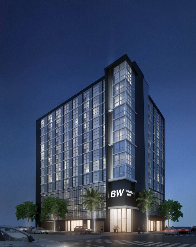 Modern high-rise building at night with illuminated windows and palm trees.