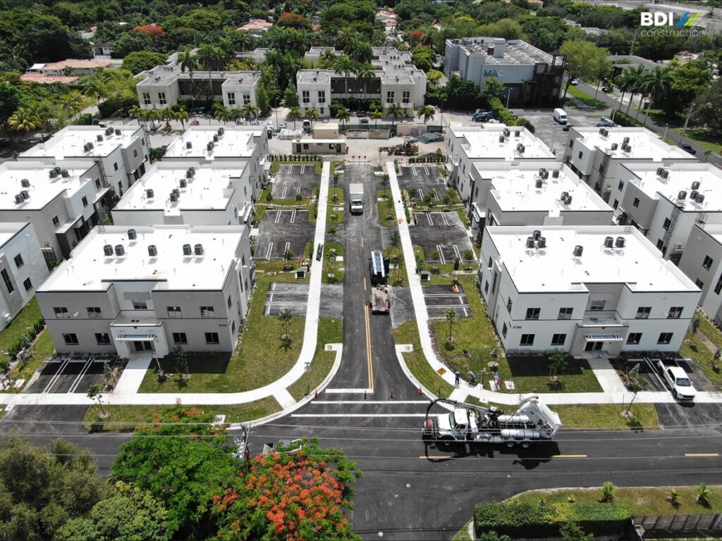 Aerial view of modern townhomes surrounded by lush greenery and tranquil streets.