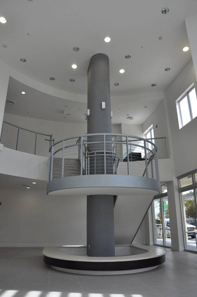 Modern architectural interior with circular staircase and sleek metal railing in a bright, spacious room.