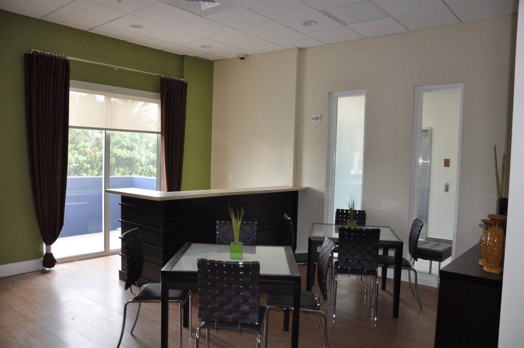 Modern café with sleek black tables, wicker chairs, and a large window letting in natural light.