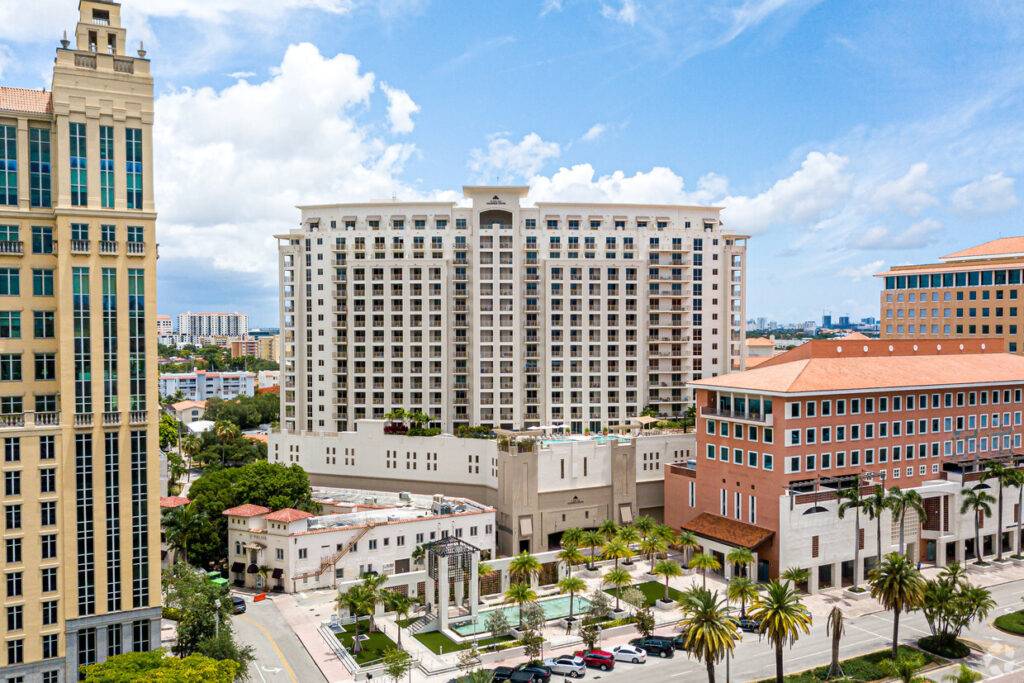 Aerial view of Columbus Center in Coral Gables, showcasing modern architecture and surrounding palm trees under a blue sky.