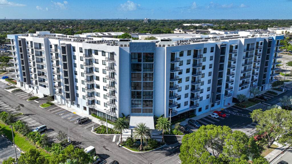 Aerial view of a modern apartment building with solar panels in an urban area.