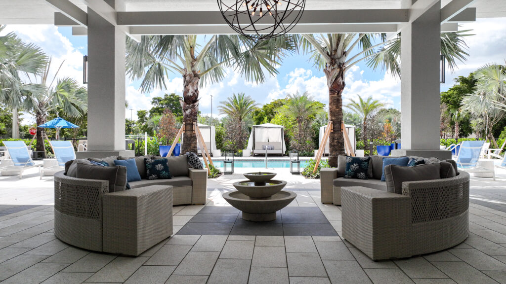 Luxurious outdoor lounge area with stylish seating and a view of a palm-lined tropical pool.