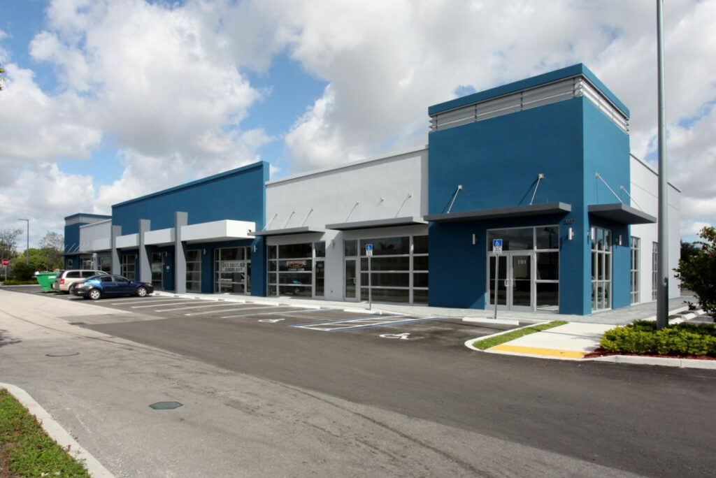Contemporary retail center with blue and white exterior featuring glass front doors and a spacious parking area.