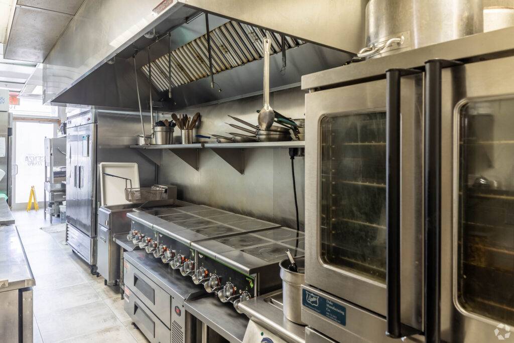 Modern commercial kitchen with industrial appliances and stainless steel surfaces