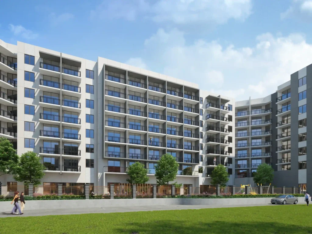 Modern residential complex with multiple floors and expansive glass balconies set against a blue sky.