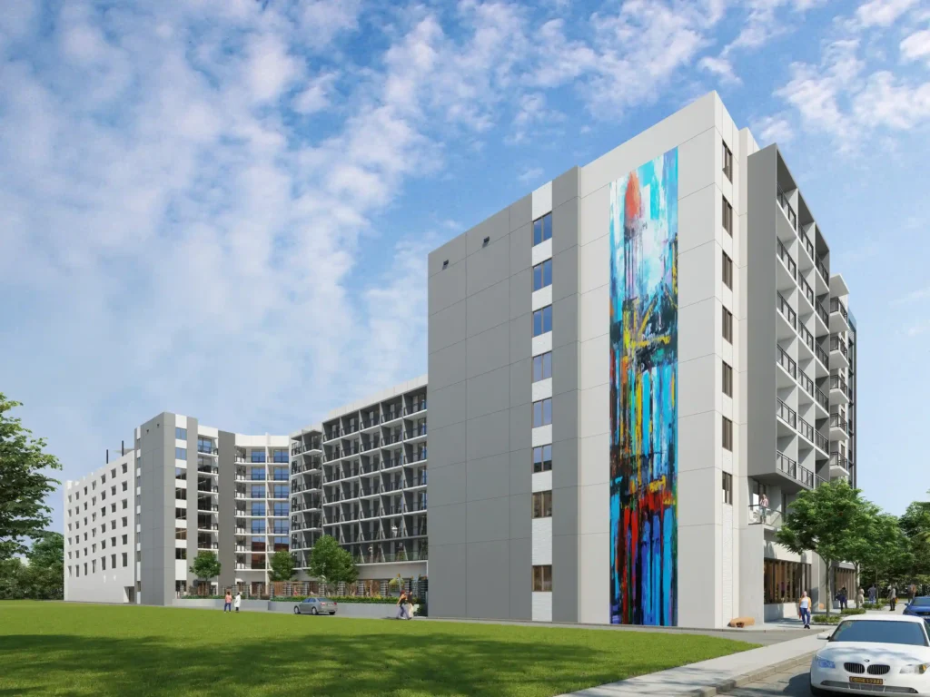 Modern apartment buildings with colorful mural under a blue sky.