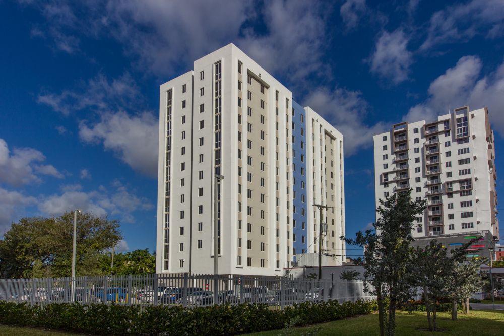 Modern high-rise apartment buildings under a vibrant blue sky with scattered clouds.