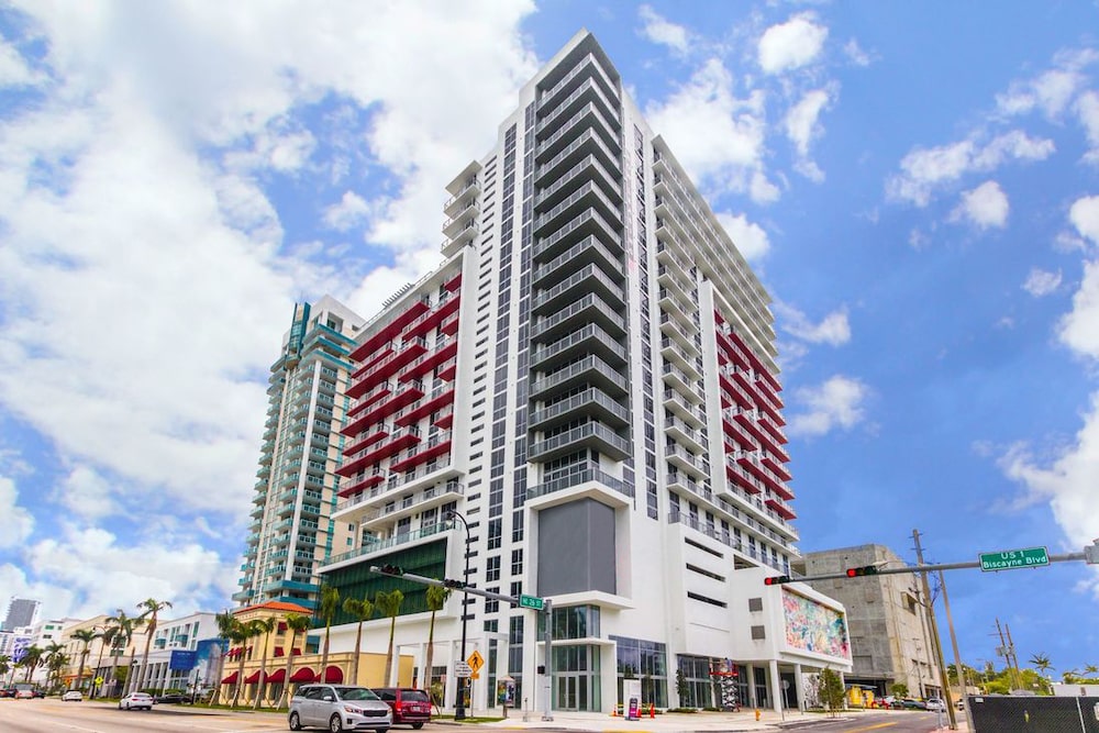 Modern high-rise building with bold red accents against a bright blue sky.