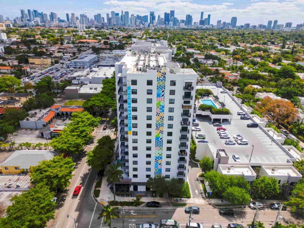 Aerial view of a modern high-rise building with colorful facade in a vibrant urban landscape.
