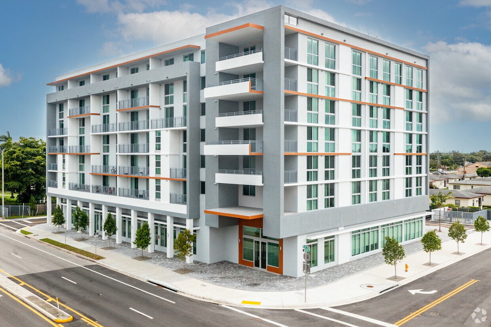 Modern apartment building with white and orange accents on a sunny day.