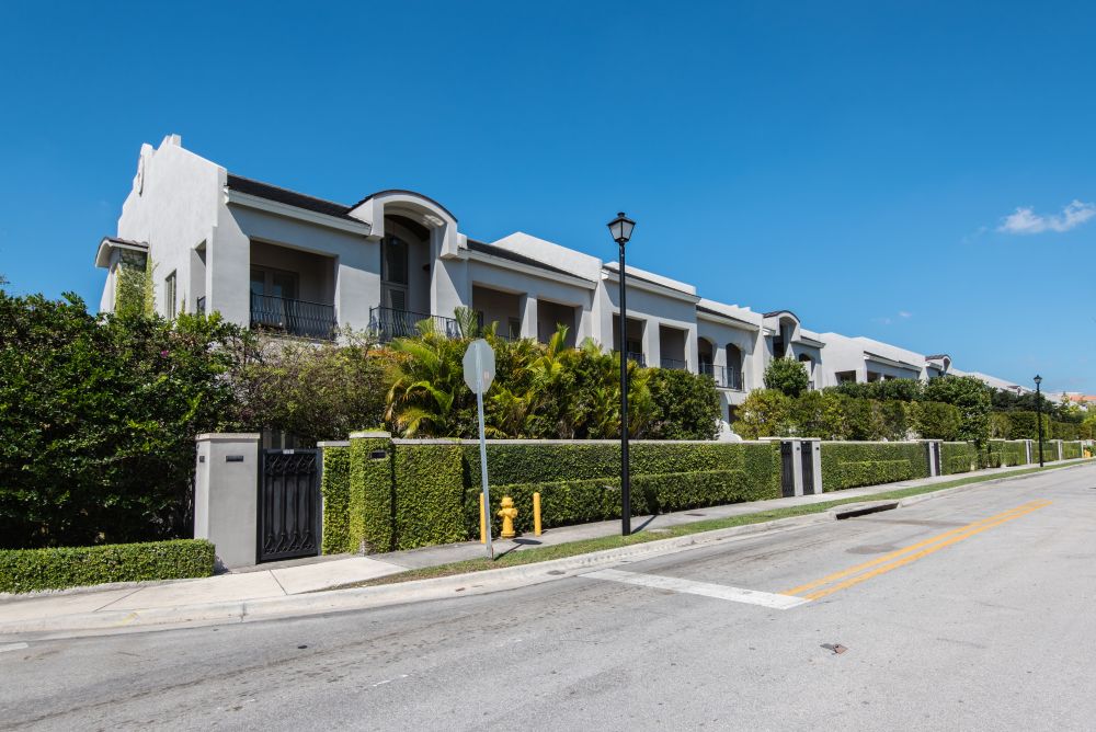 Modern row of townhouses with lush greenery under a clear blue sky.
