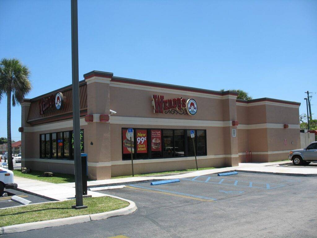 Wendy's restaurant exterior under a bright blue sky with a modern design and parking area.