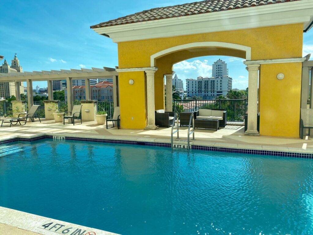 Rooftop pool with yellow archway and city skyline in the background.