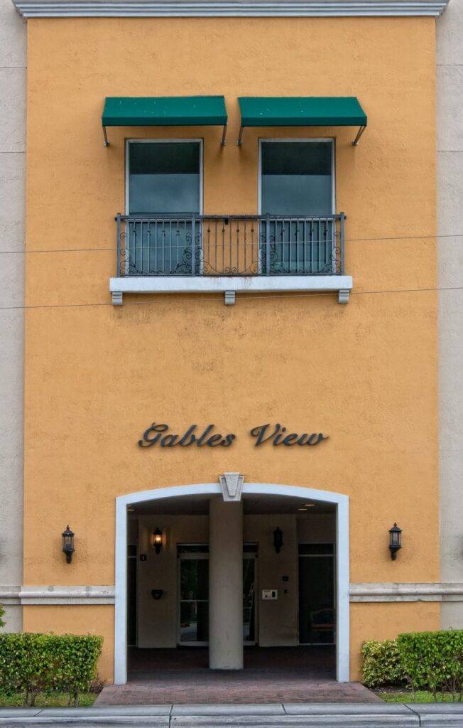 Vibrant orange building facade with green awnings and "Gables View" sign above a charming entrance.