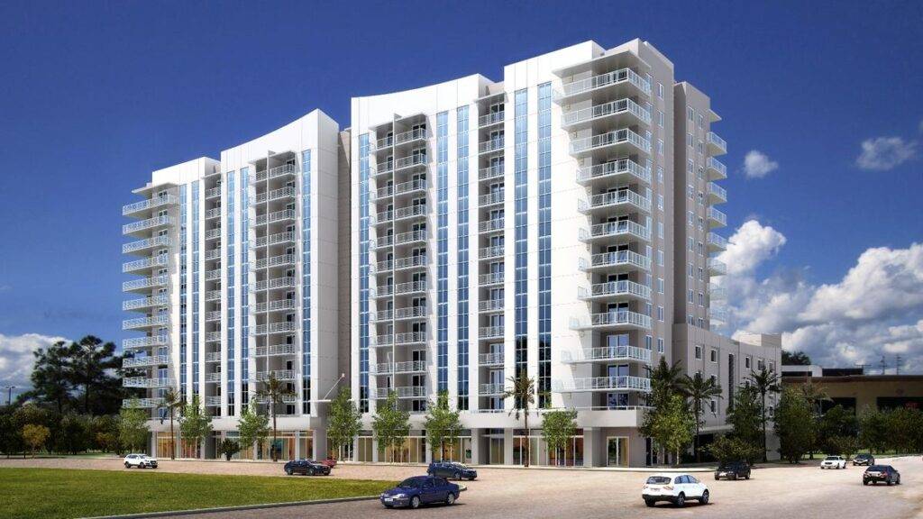 Modern high-rise building with sleek balconies and glass windows against a clear sky.