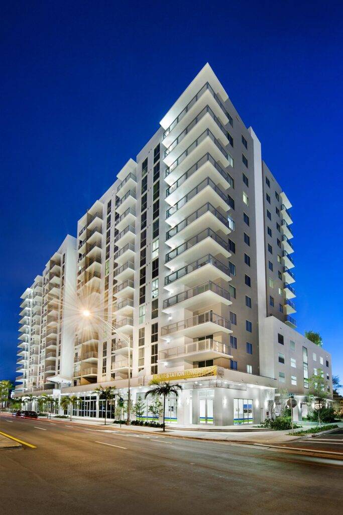 Modern high-rise building lit up against a twilight sky, showcasing sleek architecture and vibrant city life.