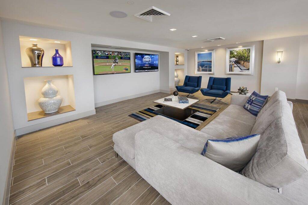 Modern living room with plush sectional, wall-mounted TVs, and stylish decor accents.