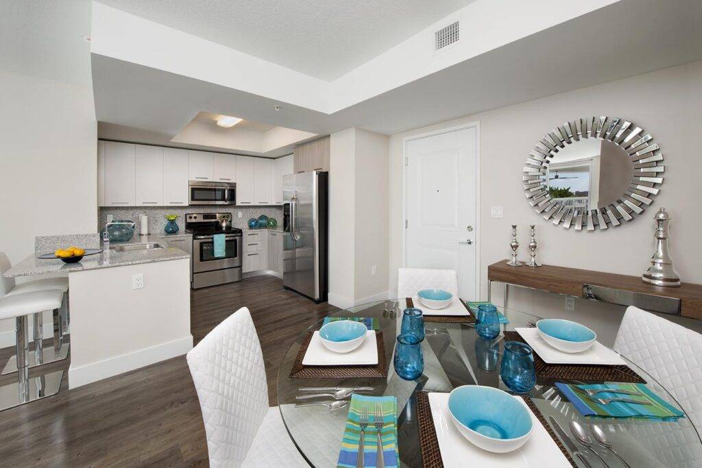 Modern kitchen and dining area in a sleek apartment with blue accents and stainless steel appliances.