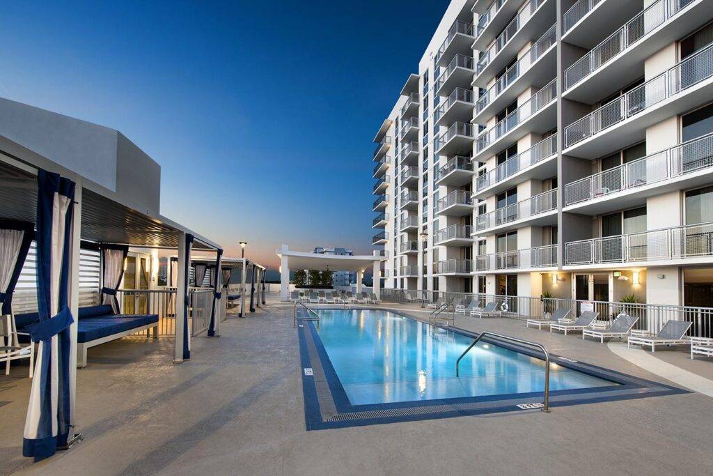 Modern apartment complex with a rooftop pool at sunset.