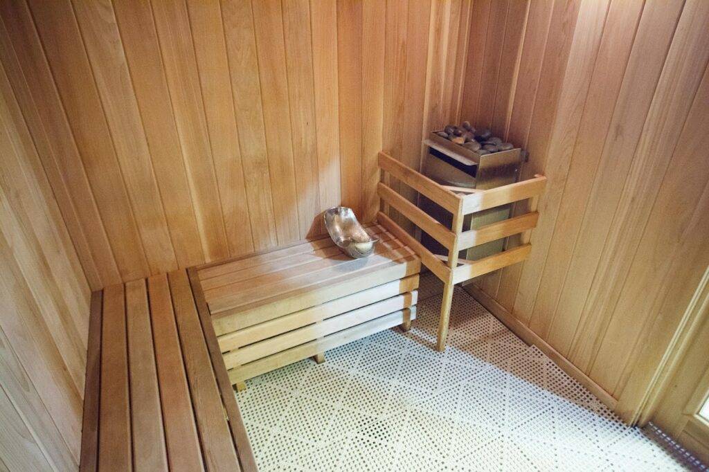 Cozy wooden sauna room with benches and a heater, offering relaxation and warmth.