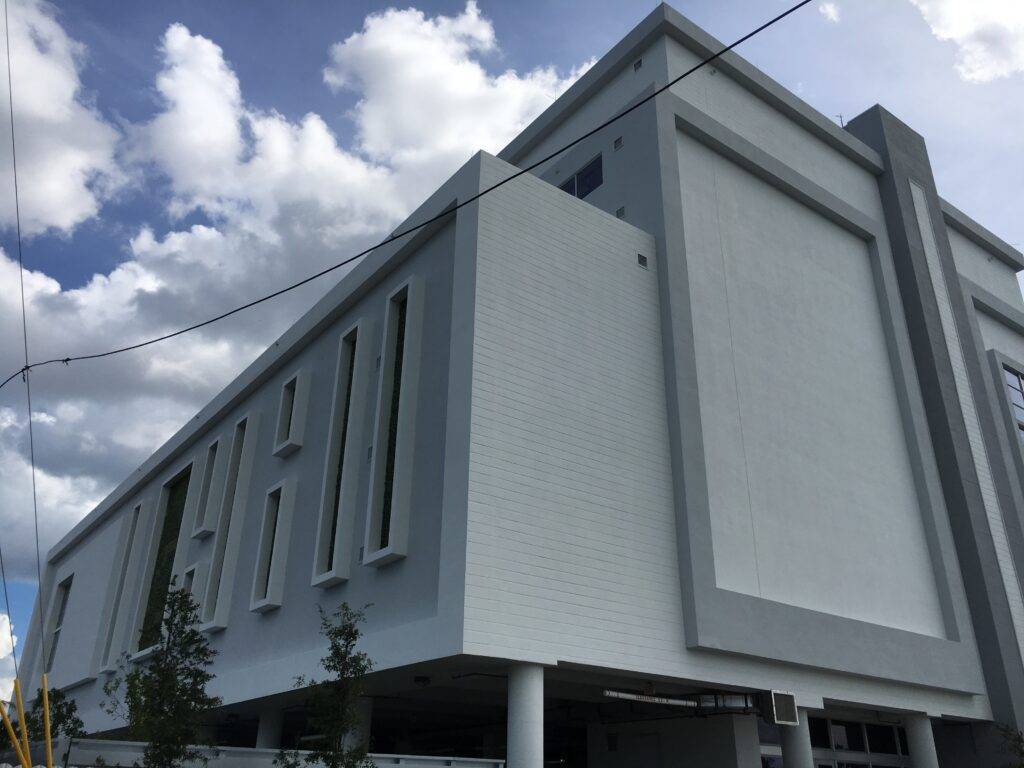 Modern white building with geometric design under a cloudy sky.