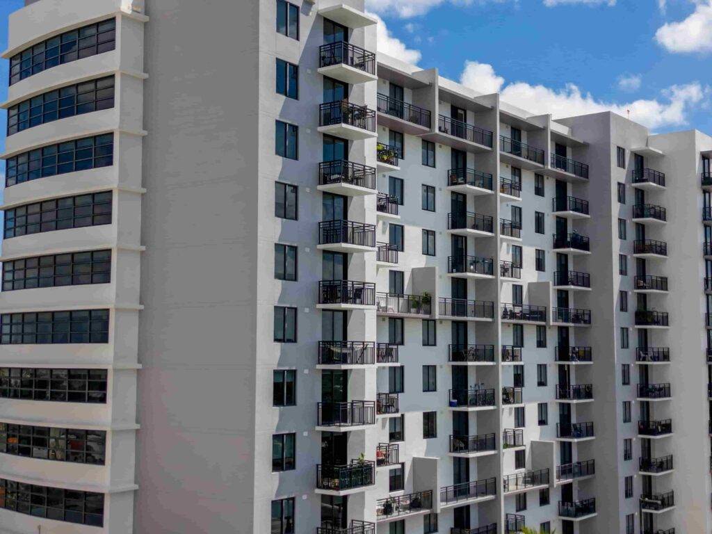 Modern high-rise apartment building with balconies and blue sky.