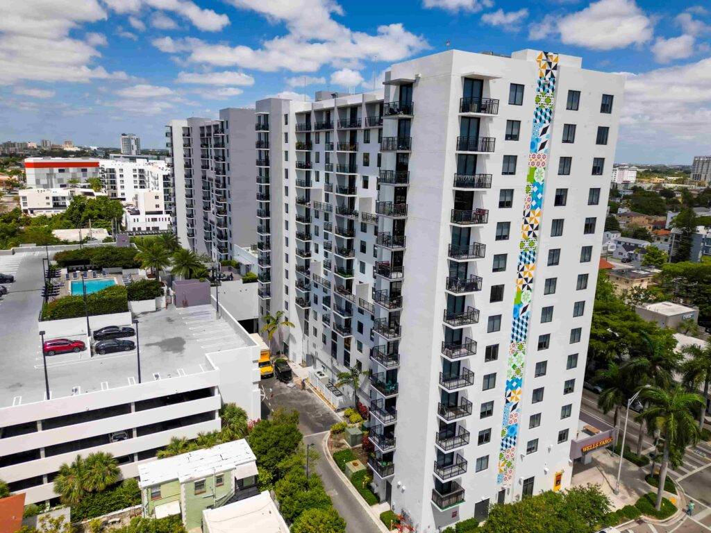Modern high-rise apartment complex with a vibrant exterior mural against a blue sky.