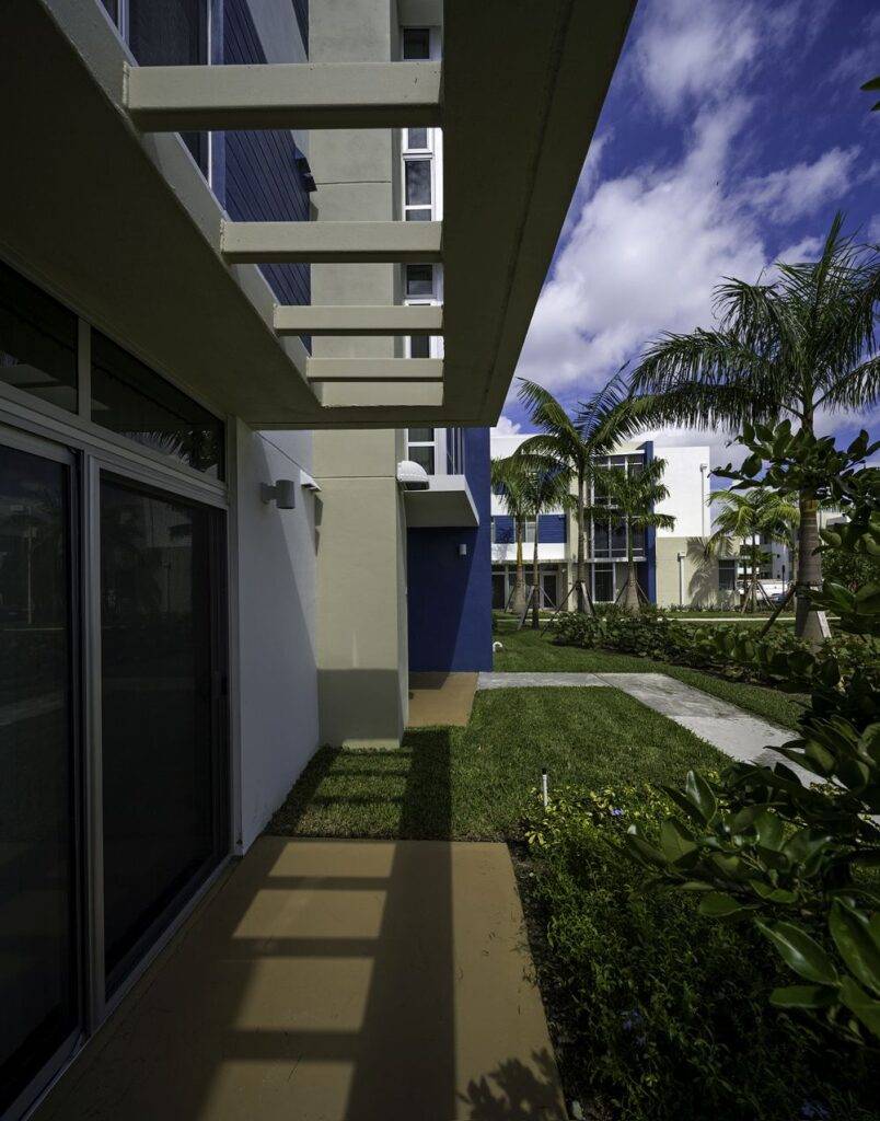 Modern residential building with sleek lines, lush greenery, and clear blue skies.