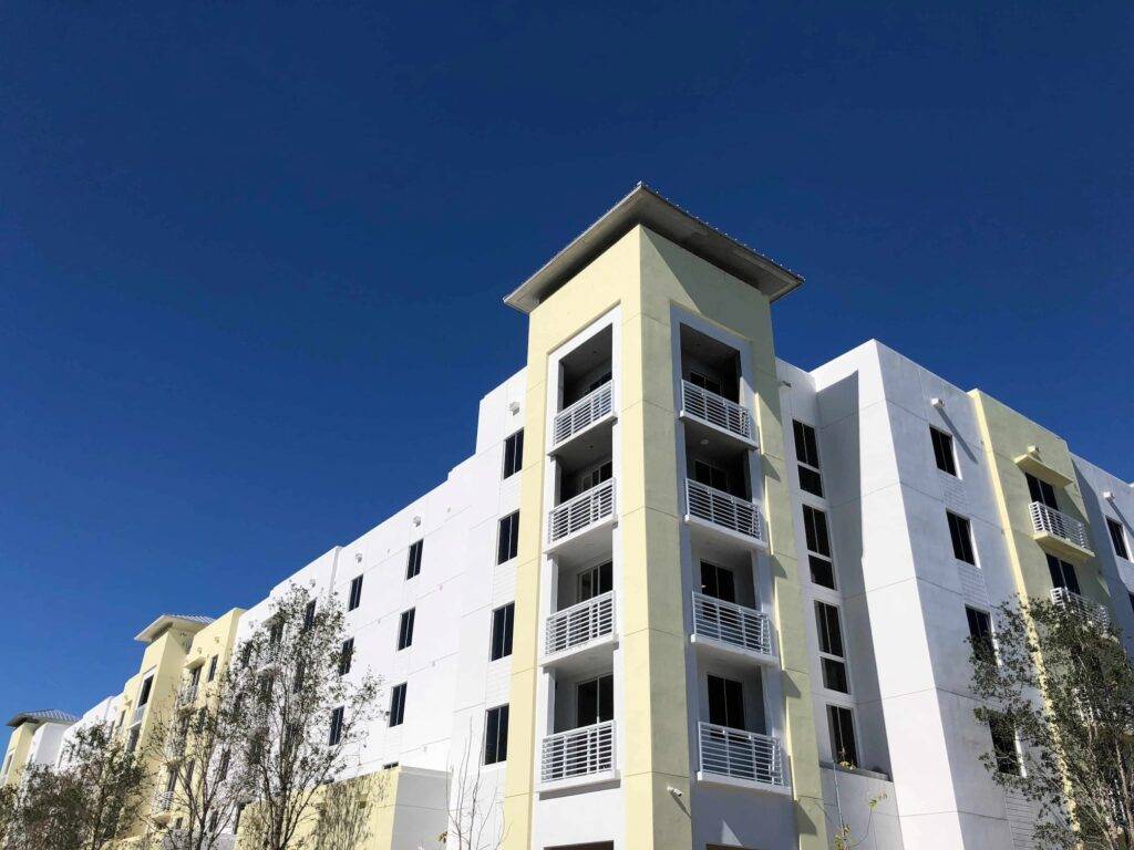 Modern white and yellow apartment building against a clear blue sky.
