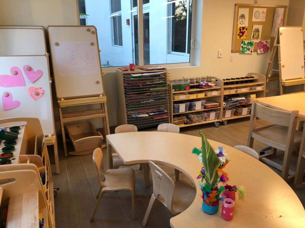 Colorful preschool classroom with art supplies and round tables, fostering creativity.