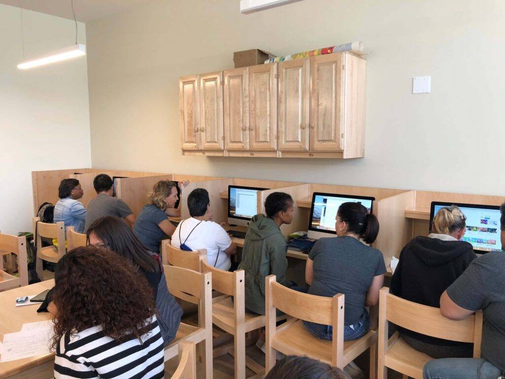 People working on computers in a cozy, well-lit room with wooden furniture.