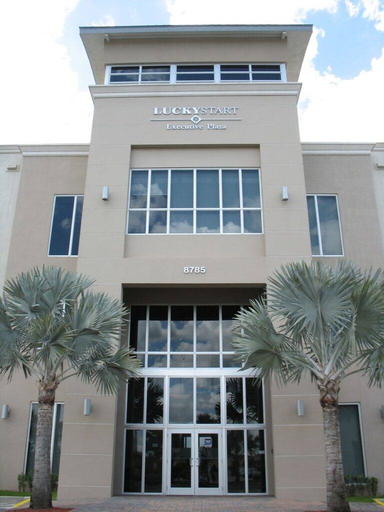 Modern office building facade with palm trees and clear sky