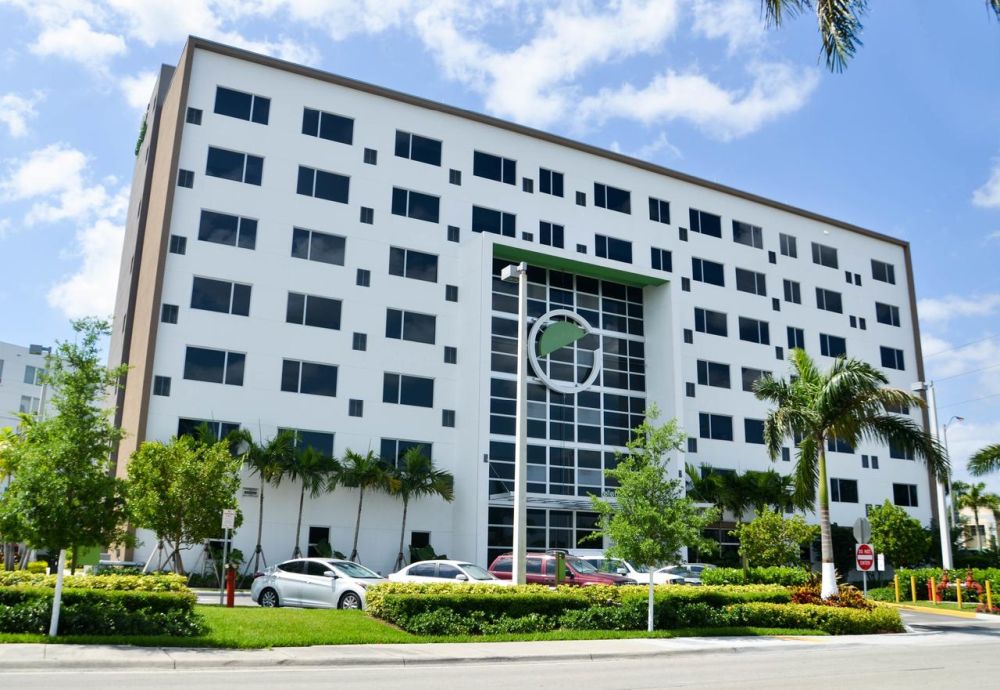 Modern multi-story office building with large windows and lush landscaping.
