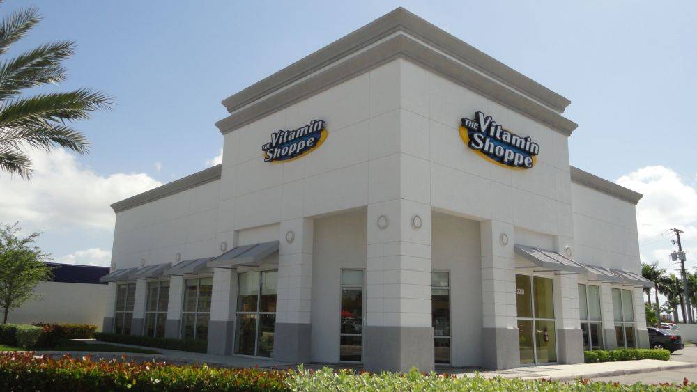 Exterior view of a Vitamin Shoppe storefront with signage and clear blue sky.