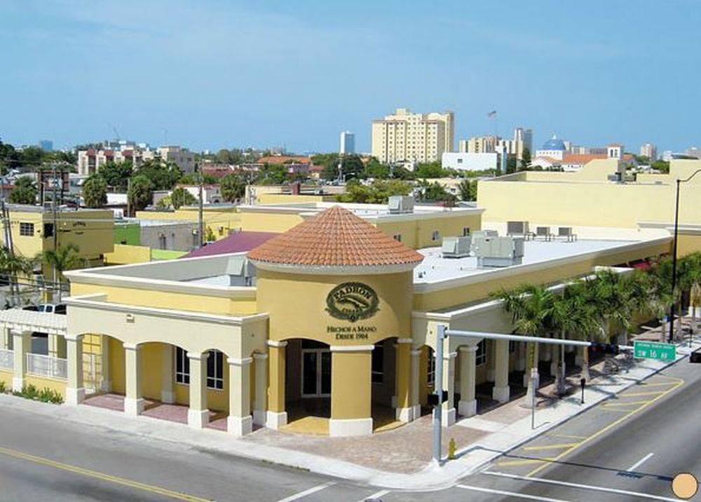 Aerial view of a vibrant yellow building amidst a bustling street in a sunny urban neighborhood.