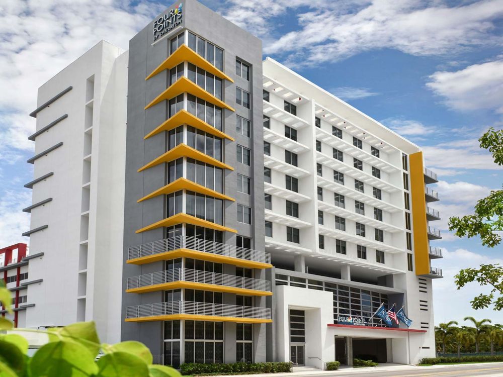 Modern multi-story building with yellow balconies against a blue sky.