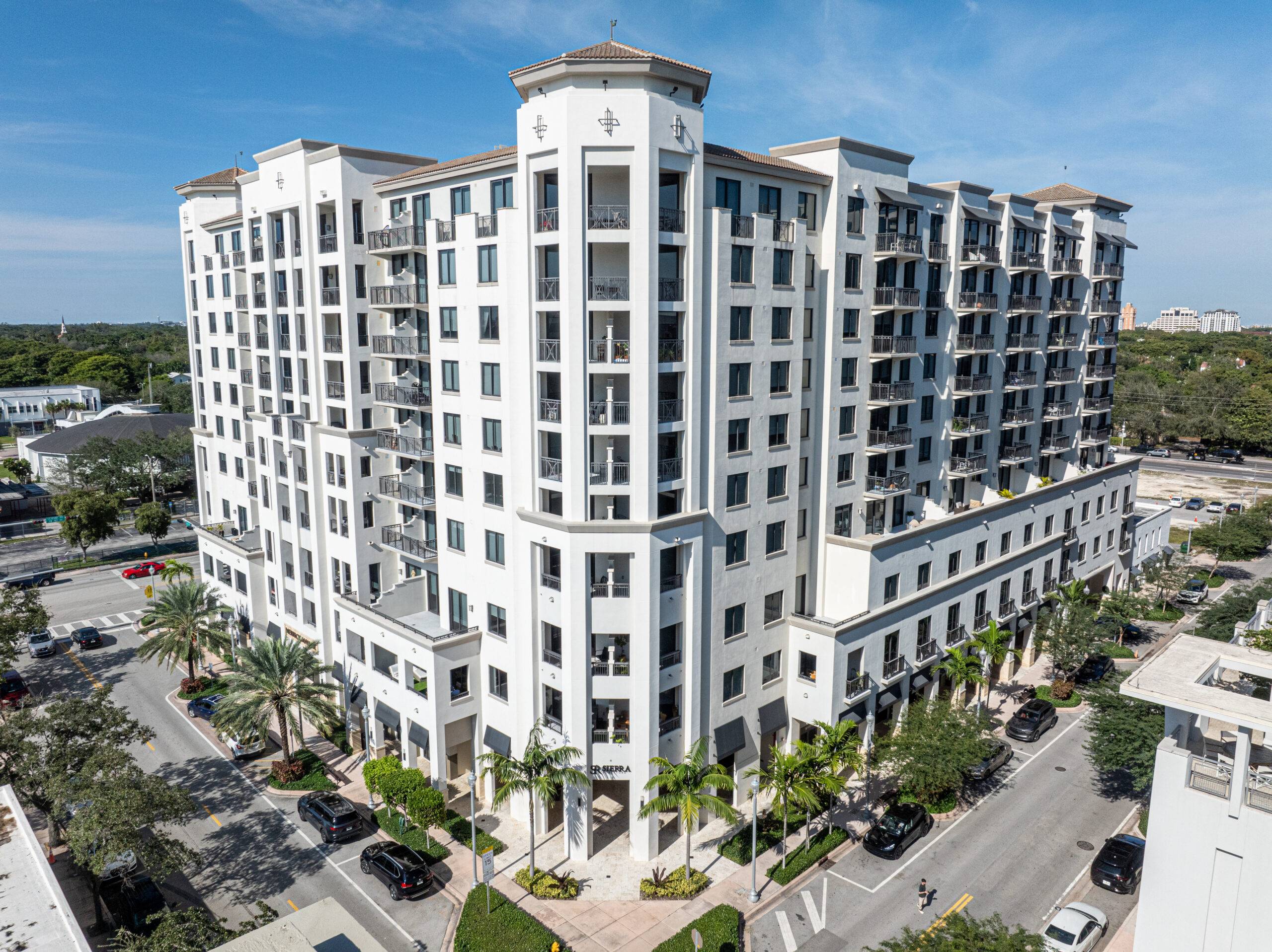 Elegant multi-story white building with palm trees in an urban setting.