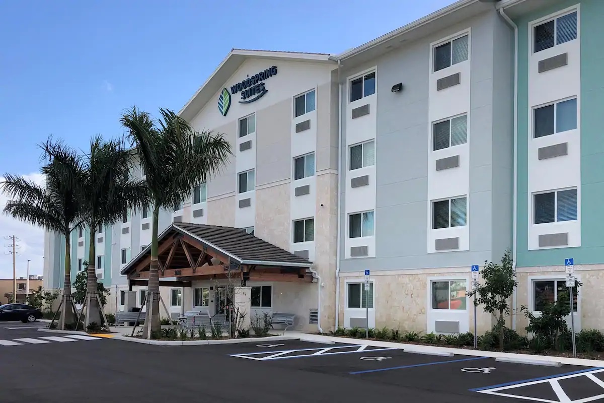 Modern hotel exterior with palm trees and a welcoming entrance.