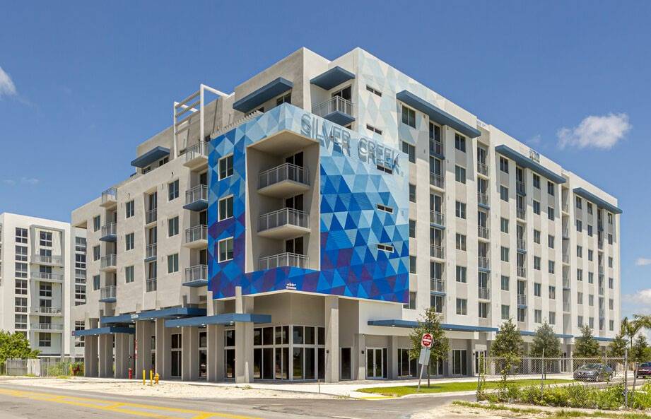 Modern blue and white geometric apartment building with balconies on a sunny day.